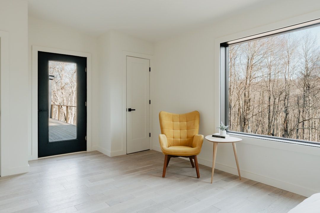 Minimalistisk inredning med gul fåtölj vid ett stort fönster.