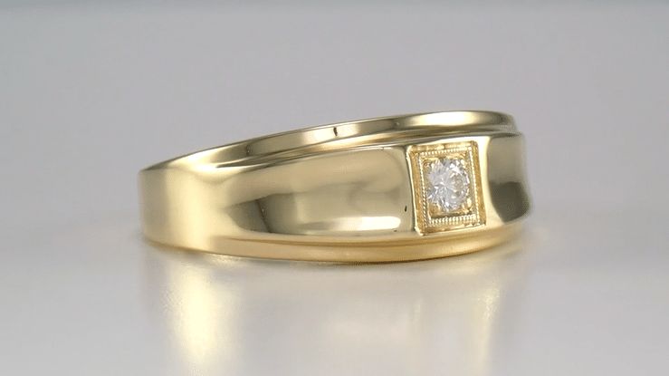 En bred vintage guldring med en infattad diamant på en ljus yta.
